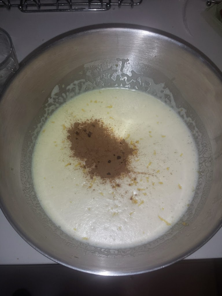 Masa cremosa en un bol metálico espolvoreada con canela y ralladura de cítricos