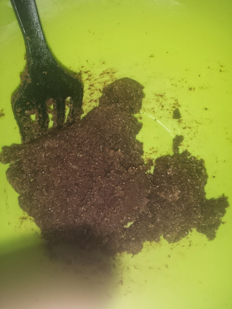 Mezcla marrón desmigada en un bol verde siendo removida con un tenedor negro